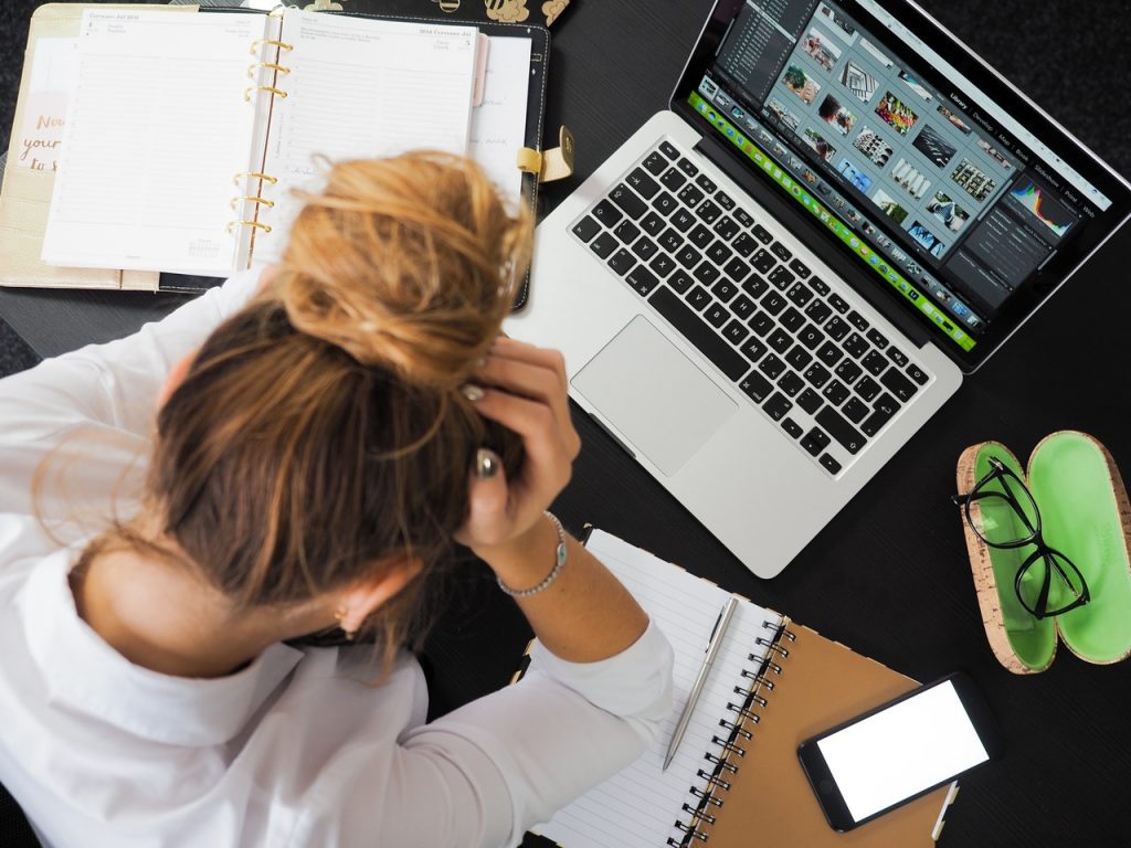 Women sitting at in front of a desk holding her head